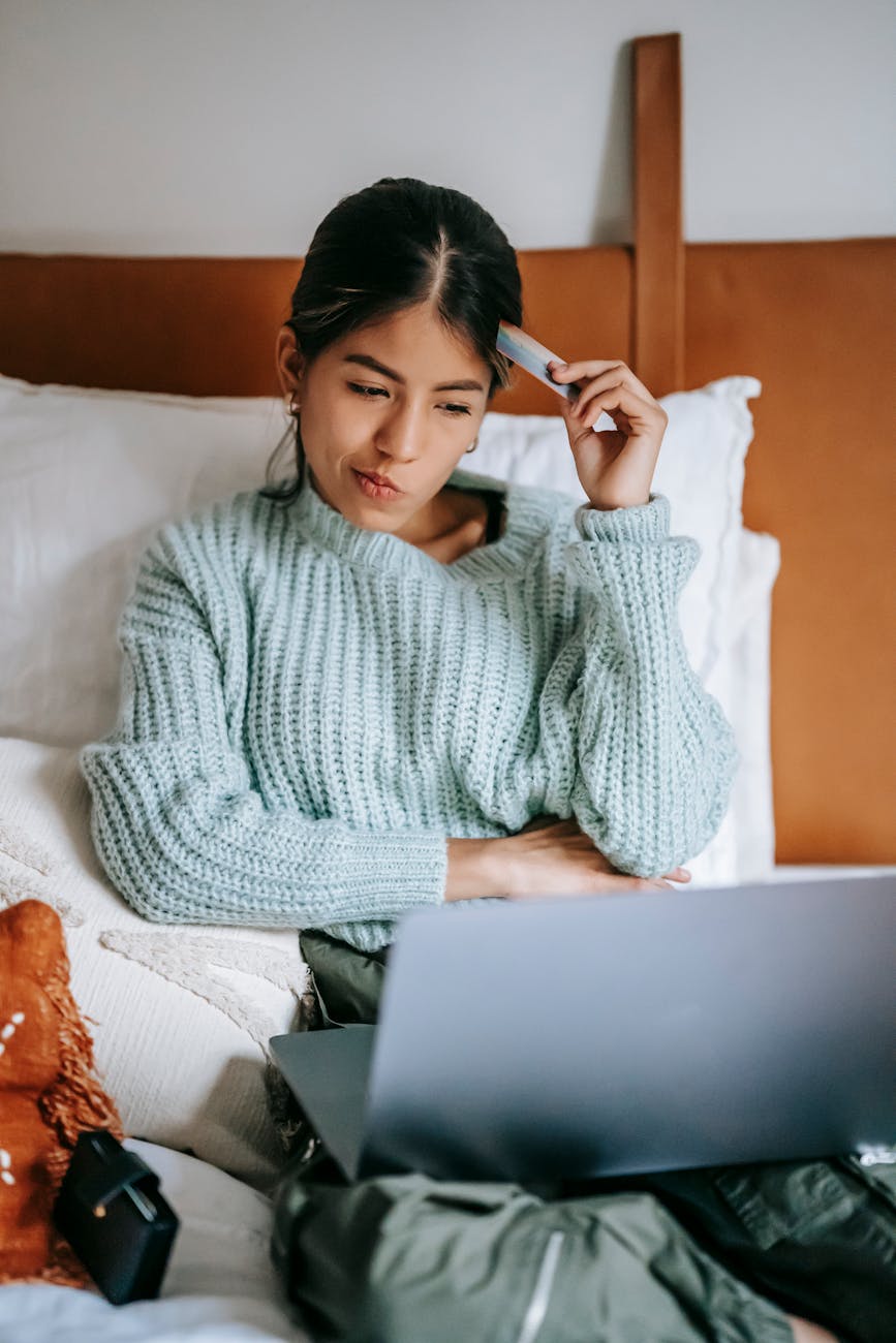 woman with credit card pondering while buying online with laptop george feola georgefeola.io