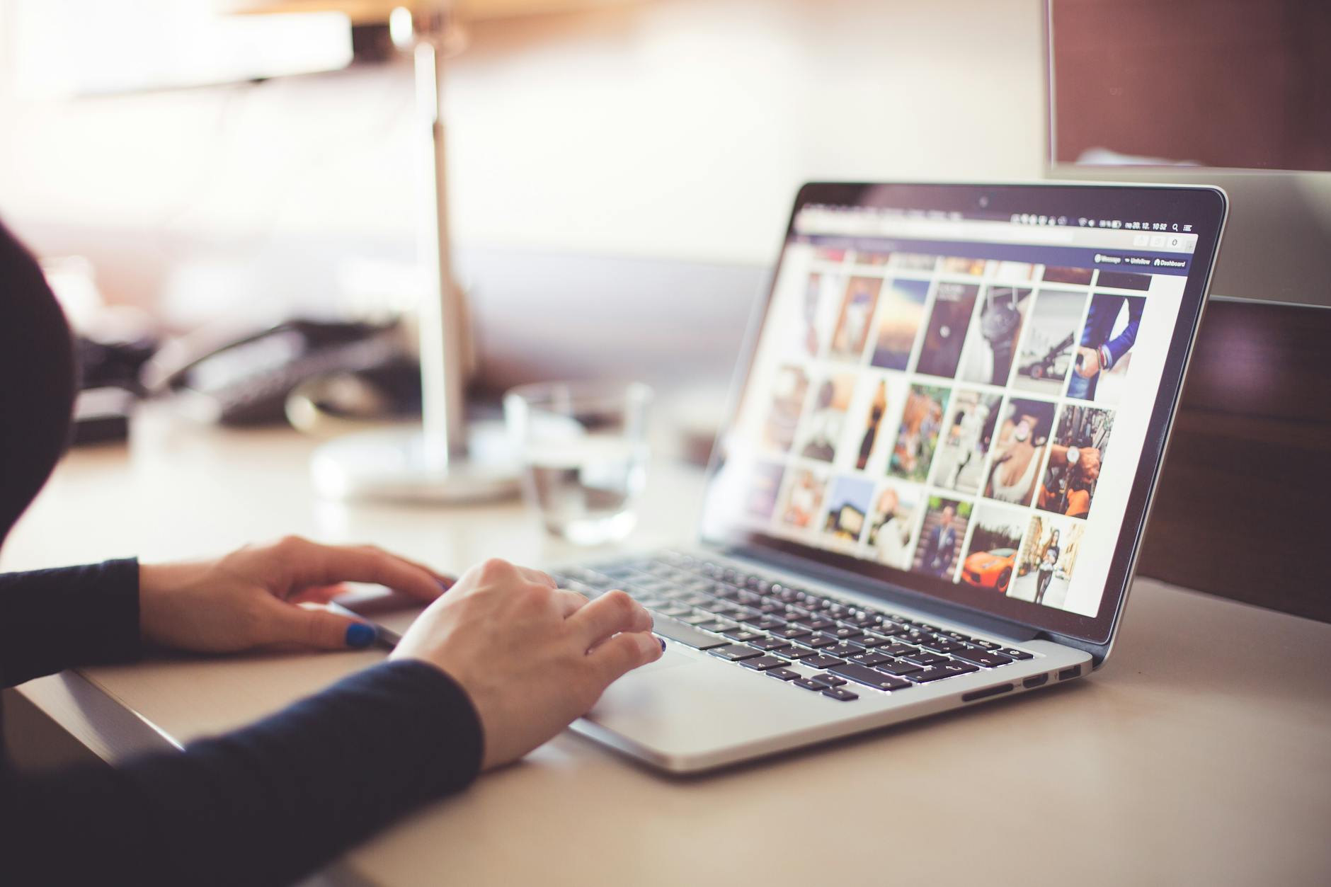 Person using a laptop to browse social media photo gallery at a desk.