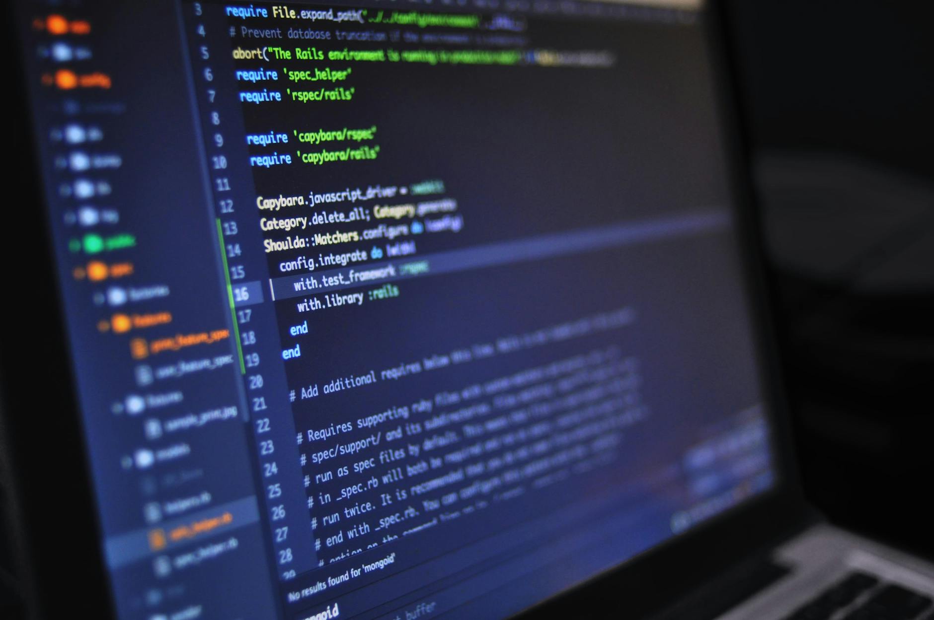 Laptop screen showing a dark-themed code editor with highlighted lines of Ruby test scripts